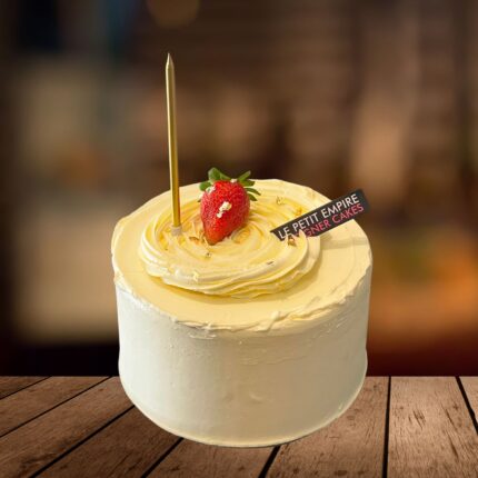 Elegant vanilla cake topped with fresh strawberry and gold flakes, perfect for special occasions and celebrations.