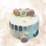Macaron cake, white drip dessert, elegant celebration cake, macarons on top, luxurious designer cake.