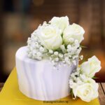 Elegant white floral wedding cake with roses and baby's breath, perfect for special celebrations.