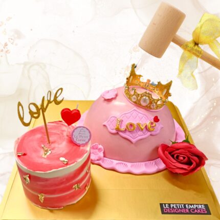 Delicate pink love-themed cake with gold crown and rose decoration, perfect for special celebrations.